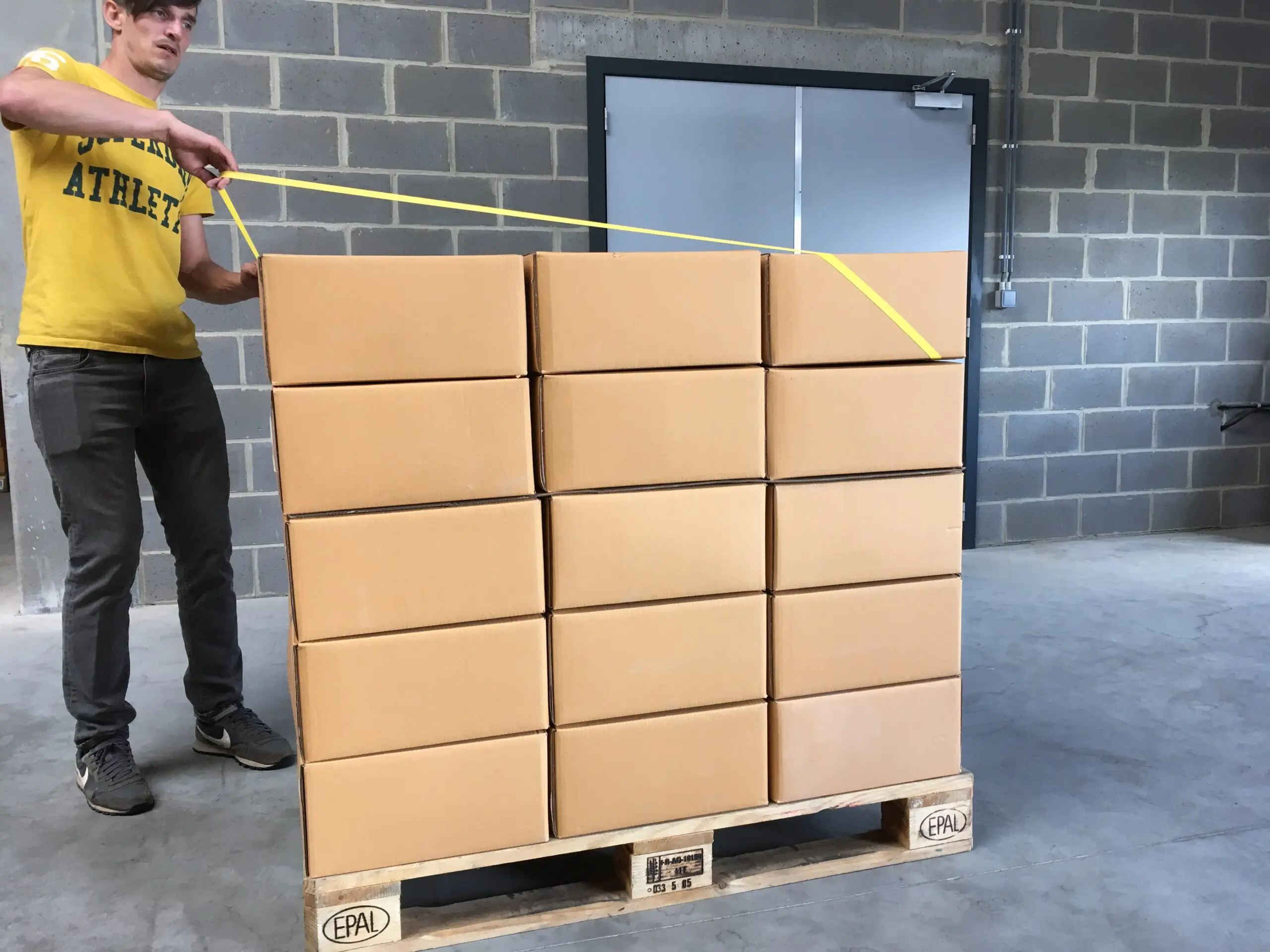Man stretching rubberband around pallet step2 scaled