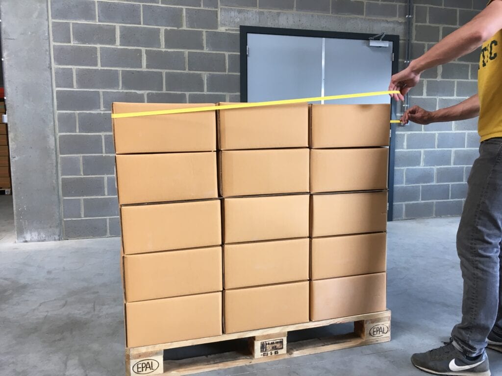 Finish by returning to your original position and fit the wedged end of the rubber band on the last corner of the pallet. Your pallet is now secured.